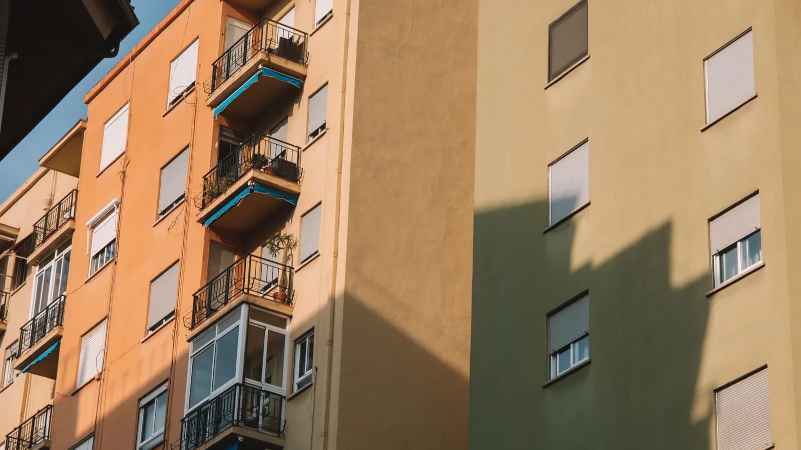 Bloques de viviendas con balcones corridos recortados a contraluz al final de la tarde